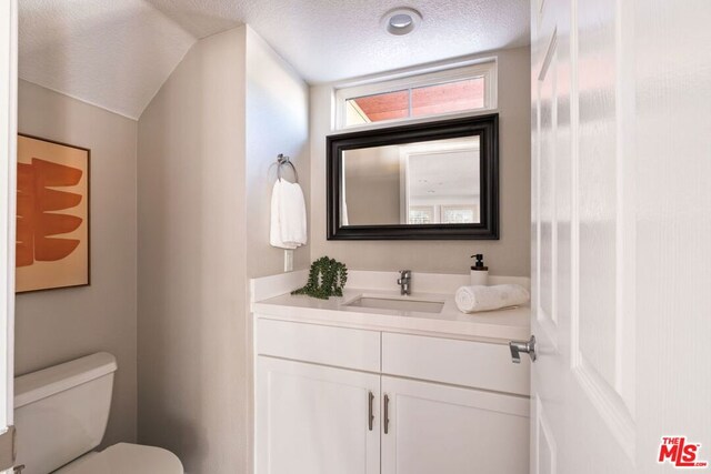 bathroom with toilet, a textured ceiling, and vanity