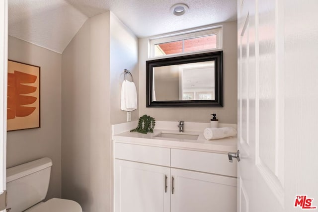 bathroom featuring toilet, vanity, and a textured ceiling