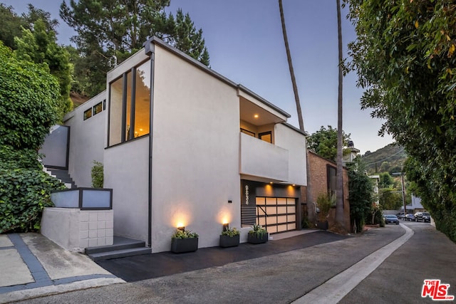 property exterior at dusk featuring a balcony and a garage