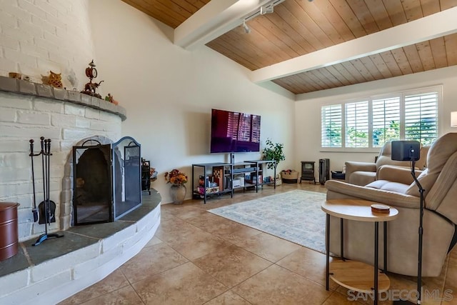 tiled living room with a large fireplace, wood ceiling, and beam ceiling