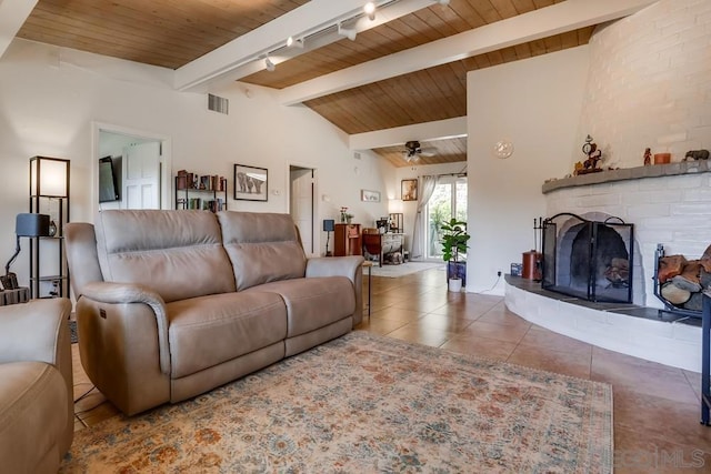 tiled living room featuring a brick fireplace, track lighting, ceiling fan, and vaulted ceiling with beams