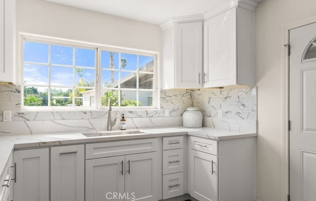 kitchen with backsplash, light stone countertops, and sink