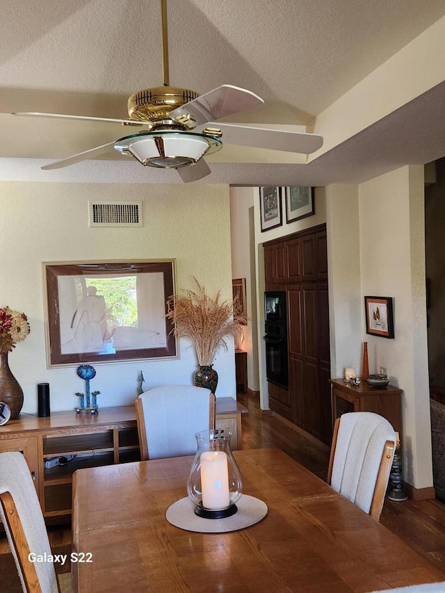 dining area featuring lofted ceiling, dark hardwood / wood-style floors, and a textured ceiling