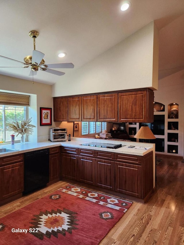 kitchen with high vaulted ceiling, black appliances, ceiling fan, kitchen peninsula, and light hardwood / wood-style flooring