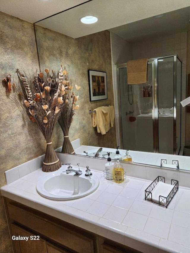 bathroom featuring a shower with door and vanity