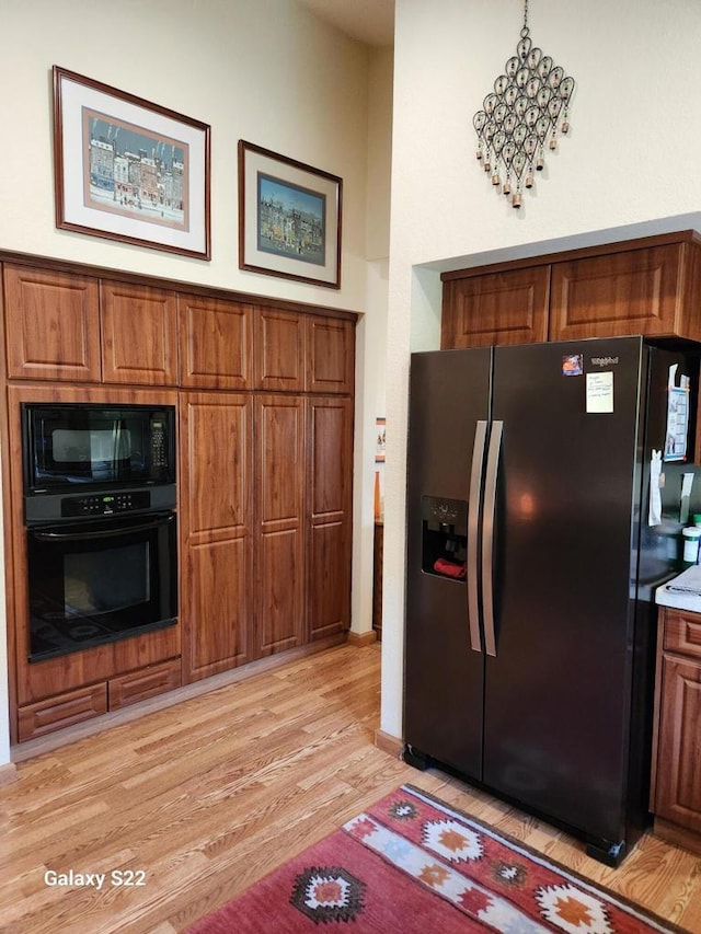 kitchen with a high ceiling, light hardwood / wood-style flooring, and black appliances