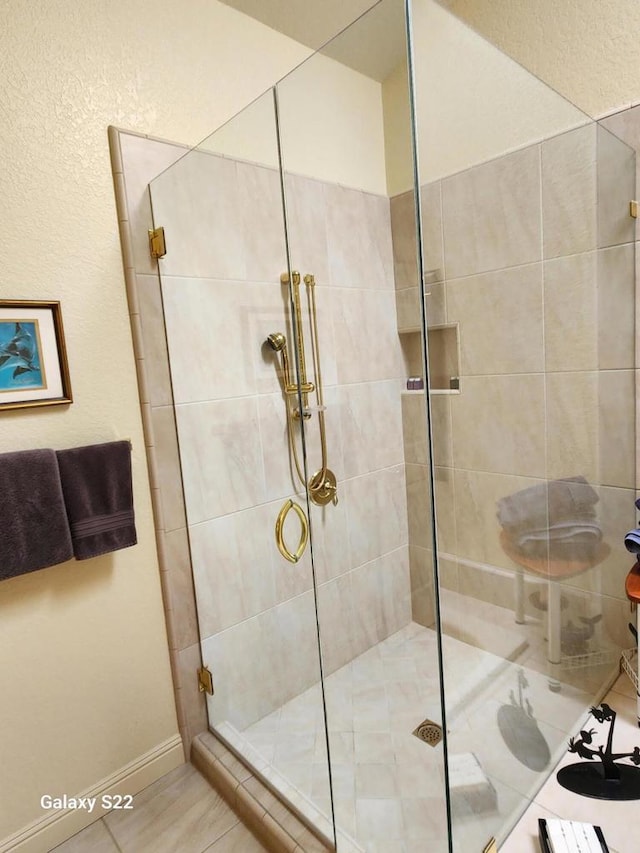 bathroom with a shower with door and tile patterned floors