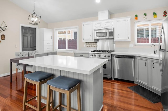 kitchen featuring sink, decorative light fixtures, white cabinets, a center island, and appliances with stainless steel finishes