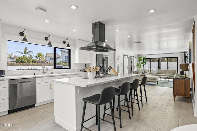 kitchen featuring appliances with stainless steel finishes, a kitchen island, white cabinetry, island exhaust hood, and a barn door