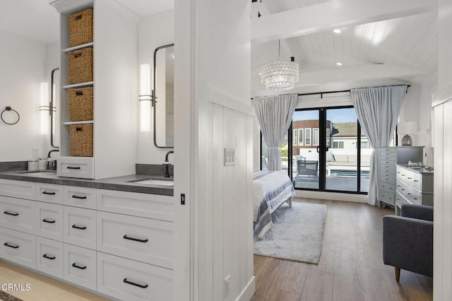 bedroom featuring sink, beam ceiling, access to outside, and light wood-type flooring