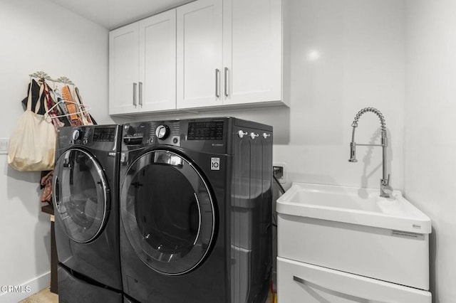 clothes washing area featuring sink, washer and clothes dryer, and cabinets