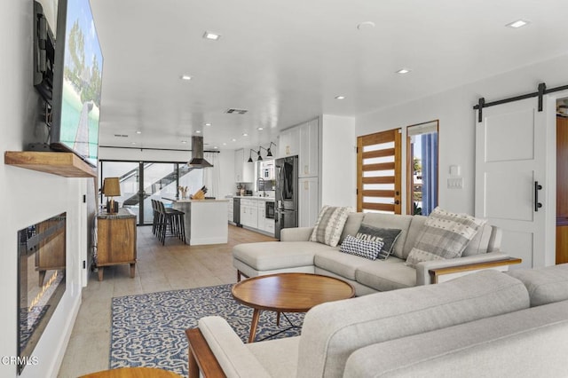 living room with sink, light hardwood / wood-style floors, and a barn door