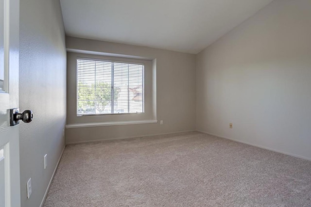 carpeted spare room with lofted ceiling