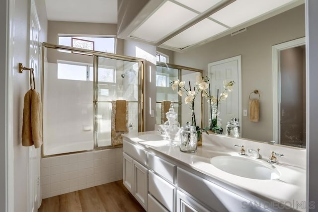 bathroom with combined bath / shower with glass door, vanity, and hardwood / wood-style flooring