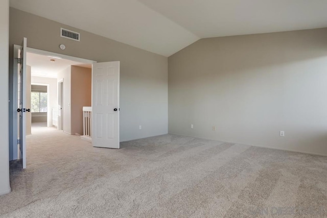 carpeted spare room with lofted ceiling