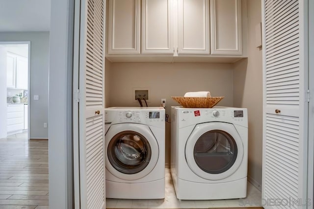 washroom with washer and dryer, light wood-type flooring, and cabinets