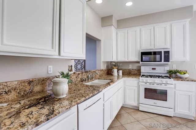 kitchen featuring white appliances, stone counters, sink, white cabinetry, and light tile patterned flooring