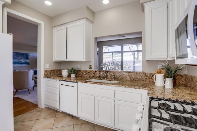 kitchen featuring white appliances, white cabinets, stone countertops, and sink