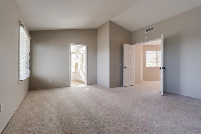 unfurnished bedroom featuring vaulted ceiling, light carpet, and connected bathroom