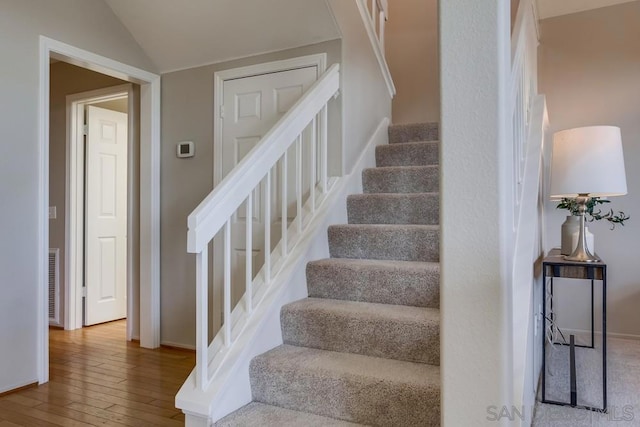 stairway featuring lofted ceiling and hardwood / wood-style floors