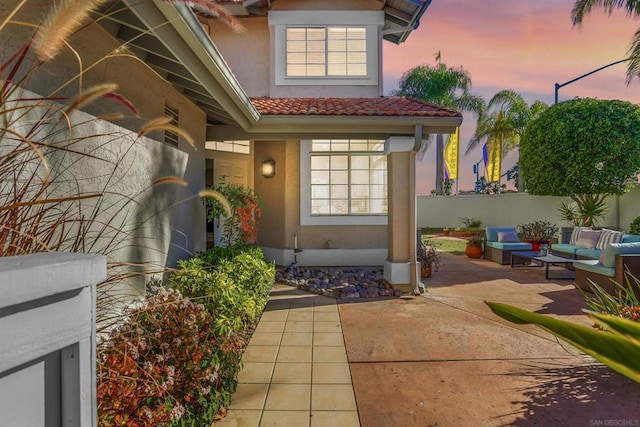 exterior entry at dusk featuring a patio area and outdoor lounge area