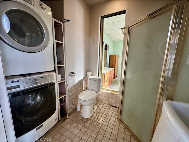 laundry room featuring stacked washing maching and dryer and light tile patterned floors