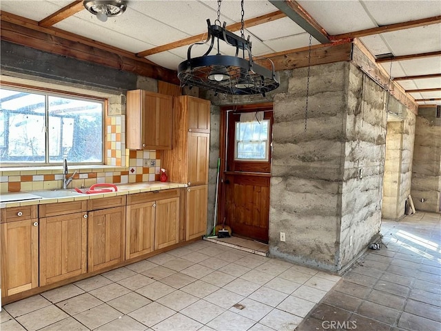 kitchen with decorative light fixtures, tile counters, tasteful backsplash, and sink