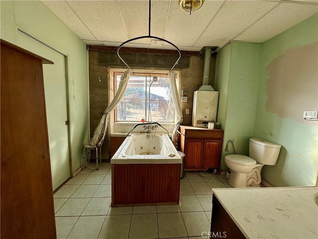 bathroom with a bathing tub, toilet, tile patterned floors, and a drop ceiling