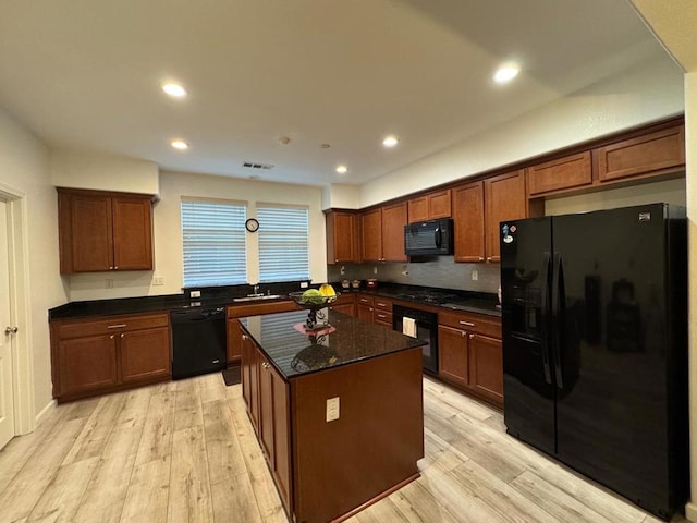 kitchen with light hardwood / wood-style floors, black appliances, decorative backsplash, a kitchen island, and dark stone counters