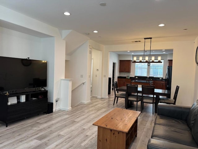 living room featuring an inviting chandelier and light hardwood / wood-style floors