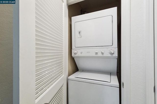 clothes washing area with stacked washer / dryer