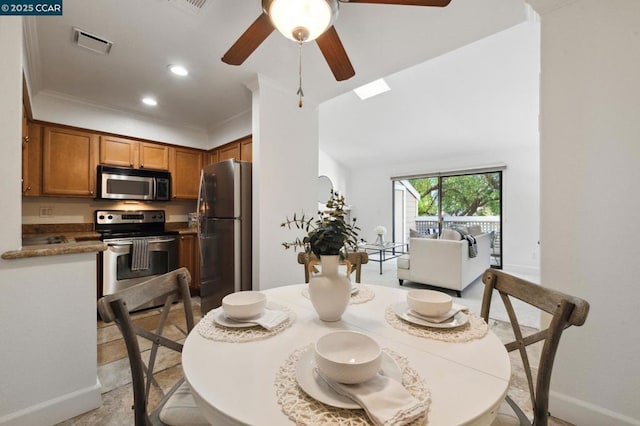 dining room featuring ornamental molding, ceiling fan, and a skylight