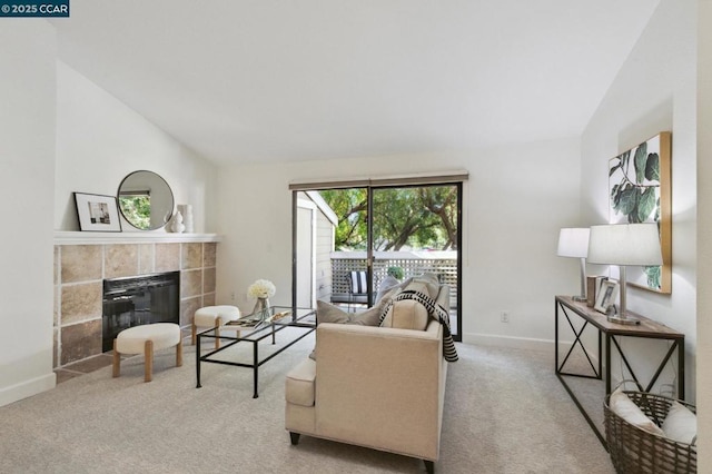 carpeted living room featuring a tile fireplace and vaulted ceiling