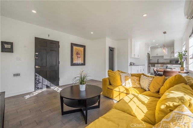 living room featuring sink, a wall mounted air conditioner, and dark hardwood / wood-style floors