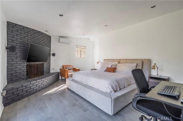 bedroom with hardwood / wood-style floors, a brick fireplace, vaulted ceiling, and a wall unit AC