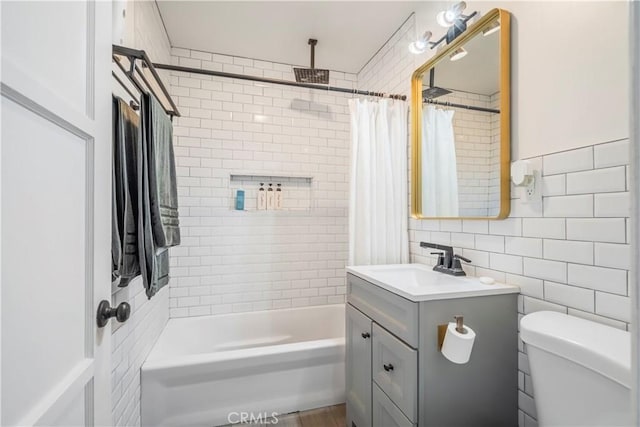 full bathroom with toilet, shower / tub combo, vanity, and tile walls