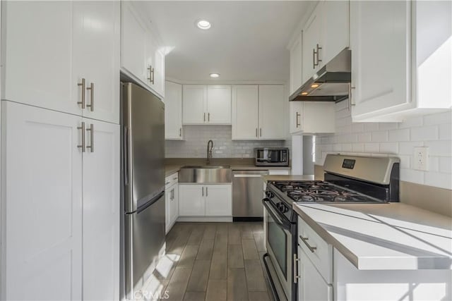 kitchen featuring dark wood-type flooring, decorative backsplash, white cabinets, appliances with stainless steel finishes, and sink