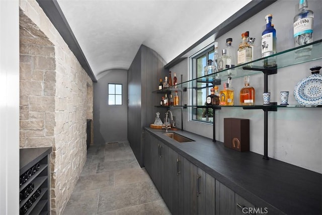 bar featuring sink, lofted ceiling, and brick ceiling