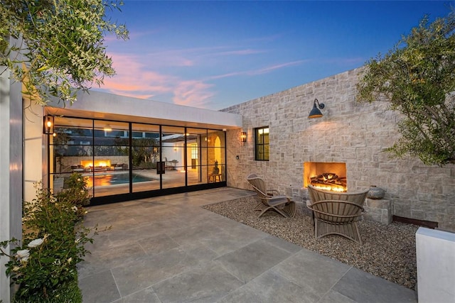 patio terrace at dusk with an outdoor stone fireplace