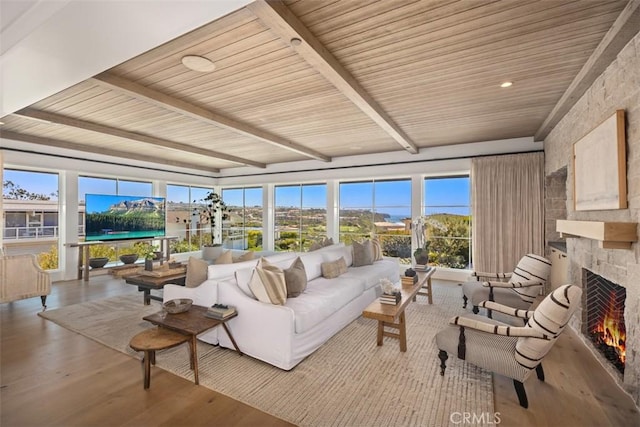 sunroom featuring beamed ceiling, wooden ceiling, and a fireplace