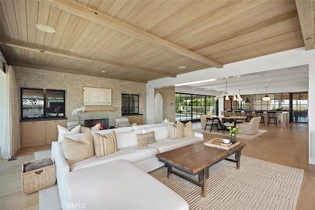 living room featuring light hardwood / wood-style floors, wooden ceiling, a fireplace, and beam ceiling