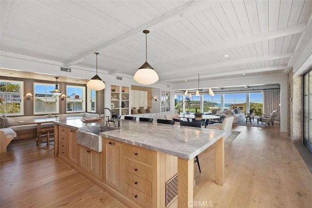 kitchen featuring sink, decorative light fixtures, a large island, light stone counters, and light brown cabinets