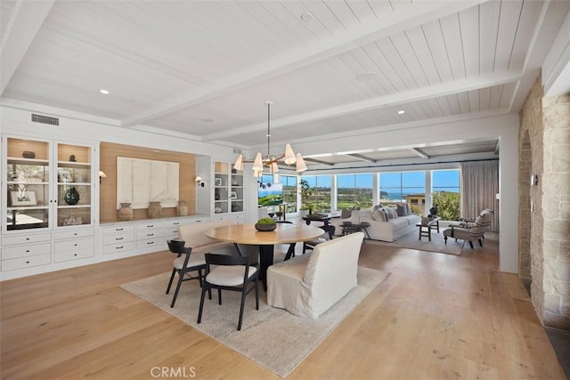 dining area with a chandelier, light hardwood / wood-style floors, and beamed ceiling