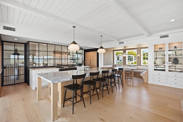 kitchen featuring beamed ceiling, white cabinets, light wood-type flooring, and pendant lighting