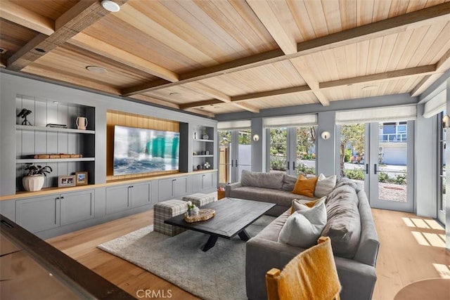 living room with french doors, built in shelves, beamed ceiling, and light hardwood / wood-style floors