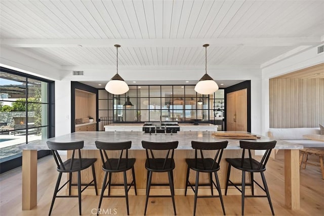 kitchen with decorative light fixtures, light wood-type flooring, and beam ceiling