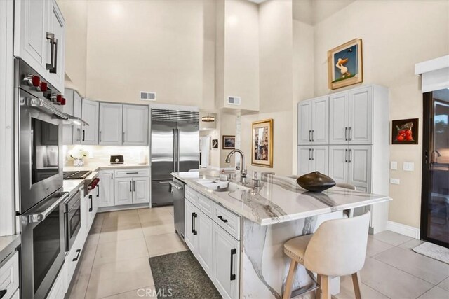 kitchen featuring sink, a high ceiling, a kitchen bar, and an island with sink