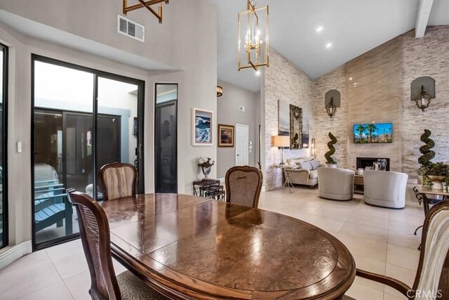 dining area featuring a large fireplace, a notable chandelier, light tile patterned floors, high vaulted ceiling, and beamed ceiling