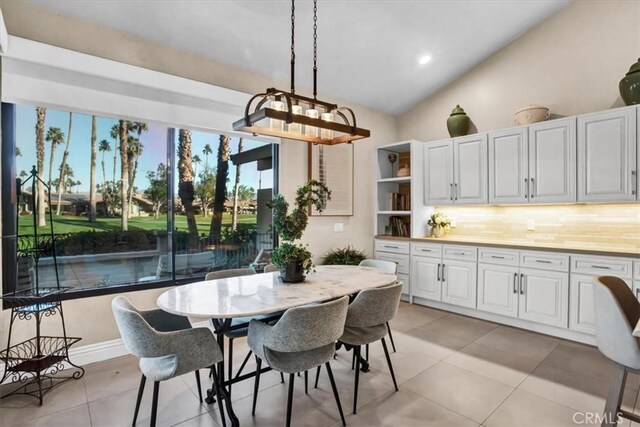 tiled dining area featuring vaulted ceiling