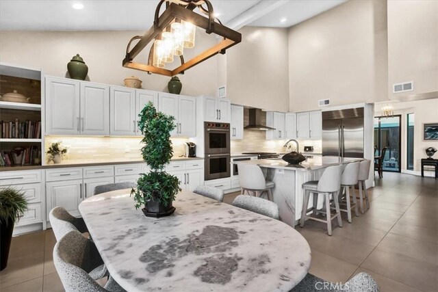 dining space featuring sink, a high ceiling, an inviting chandelier, and dark tile patterned floors